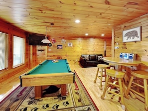 Un interior de madera con mesa de billar, sofá y zona de bar.