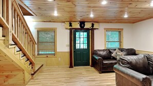 A wooden staircase leading to a green door, a leather sofa, and a wooden floor. - Big Bear 2 (Gatlinburg)