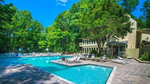 A swimming pool with lounge chairs, a brick patio, and a building with a flag. - Big Bear 2 (Gatlinburg)