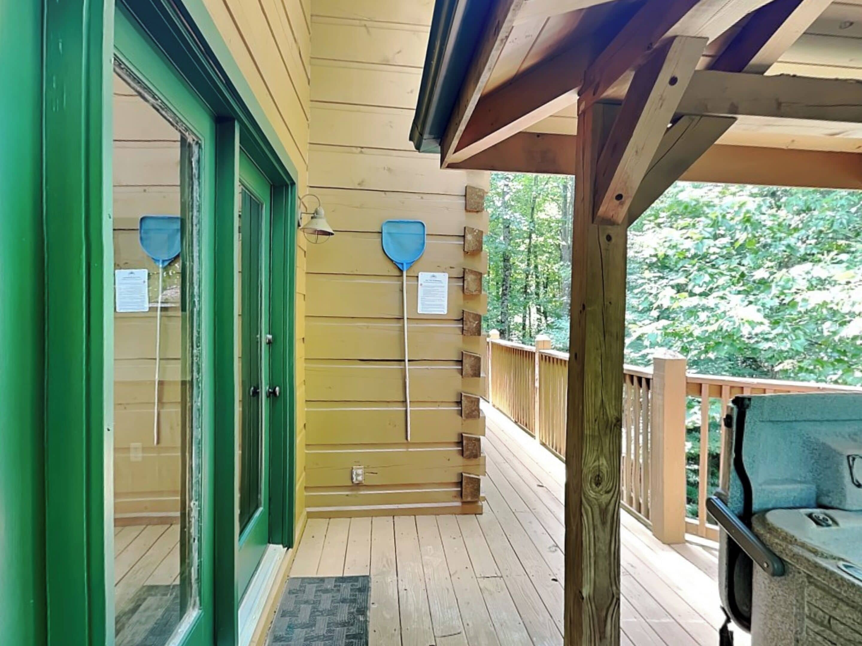 Une terrasse en bois dotée d’un espace salon couvert, d’une rambarde en bois et d’une porte à cadre vert.