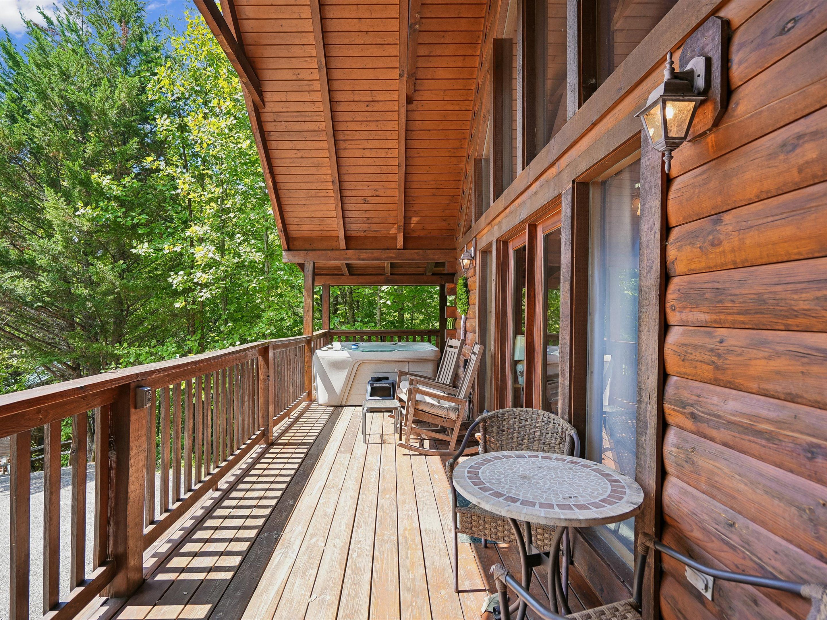 A wooden deck with a hot tub, wicker chairs, and a table.