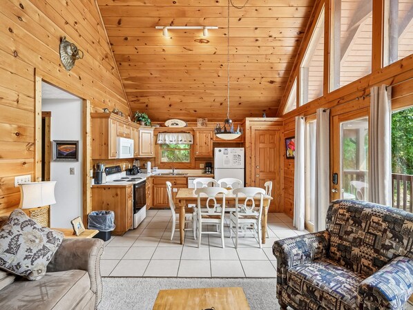 A cabin interior with a dining area, kitchen, and seating.