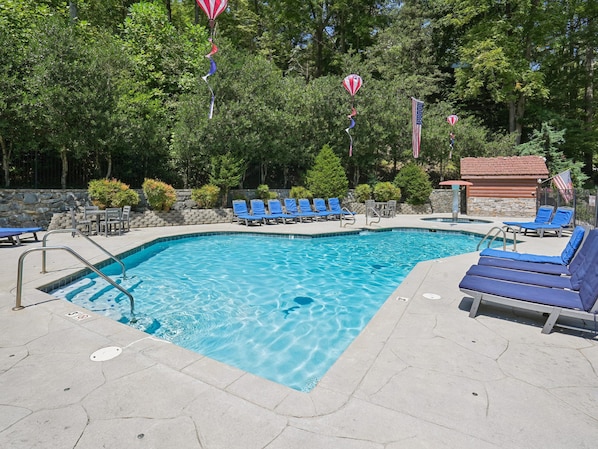 A swimming pool with blue lounge chairs and a stone wall.