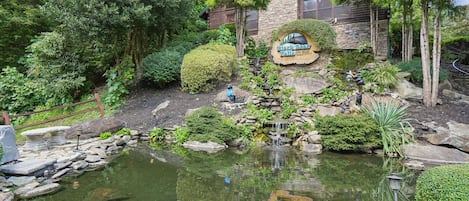 A landscaped garden with a pond, stone walls, and a wooden cabin labeled 'Black Bear Falls.'