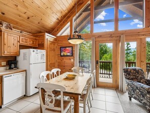 Ein Holzblockhaus-Innenraum mit Esstisch, Stühlen, einem Kühlschrank und einer Couch.