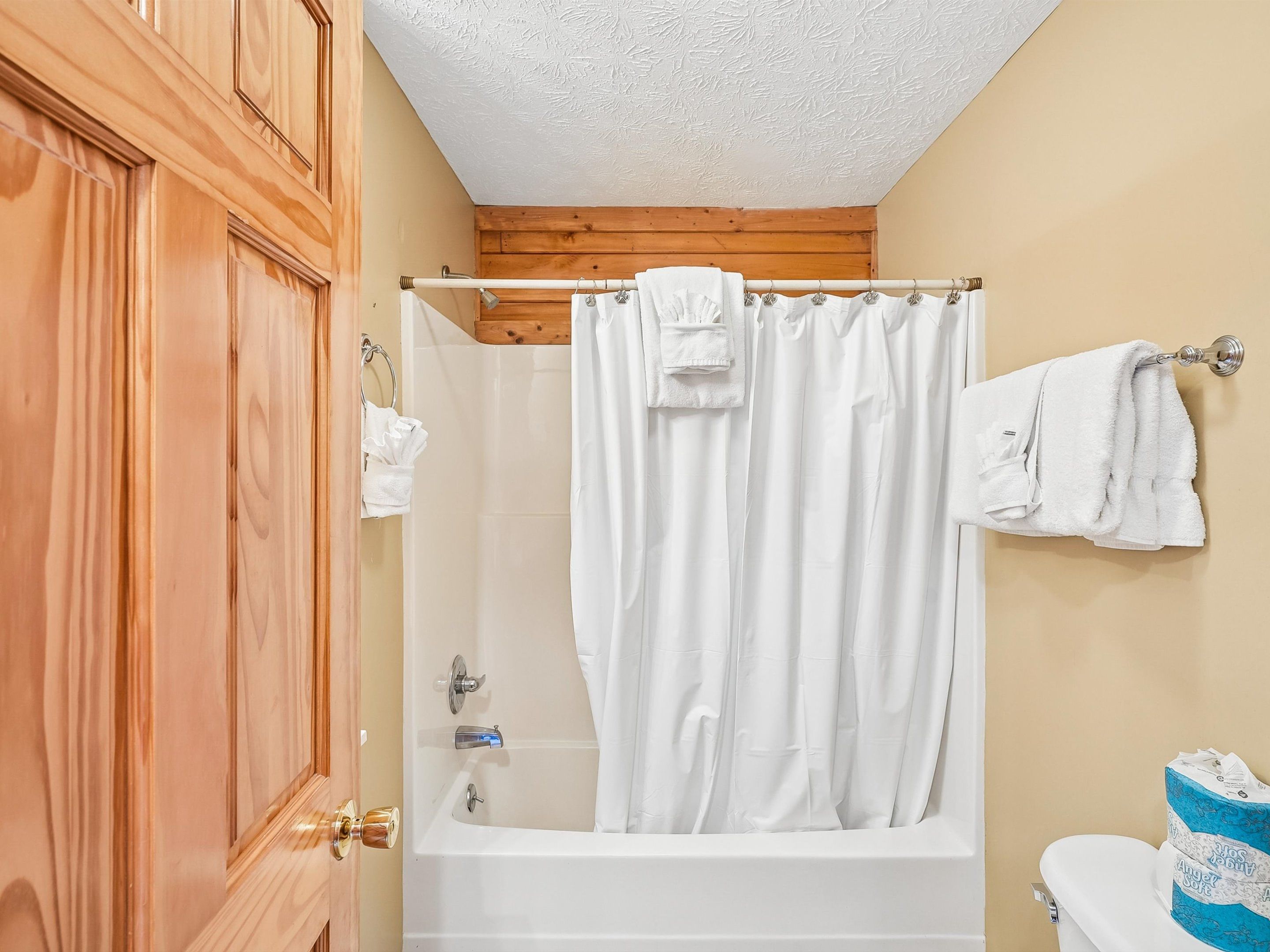 Un baño con bañera, inodoro y puerta de madera.