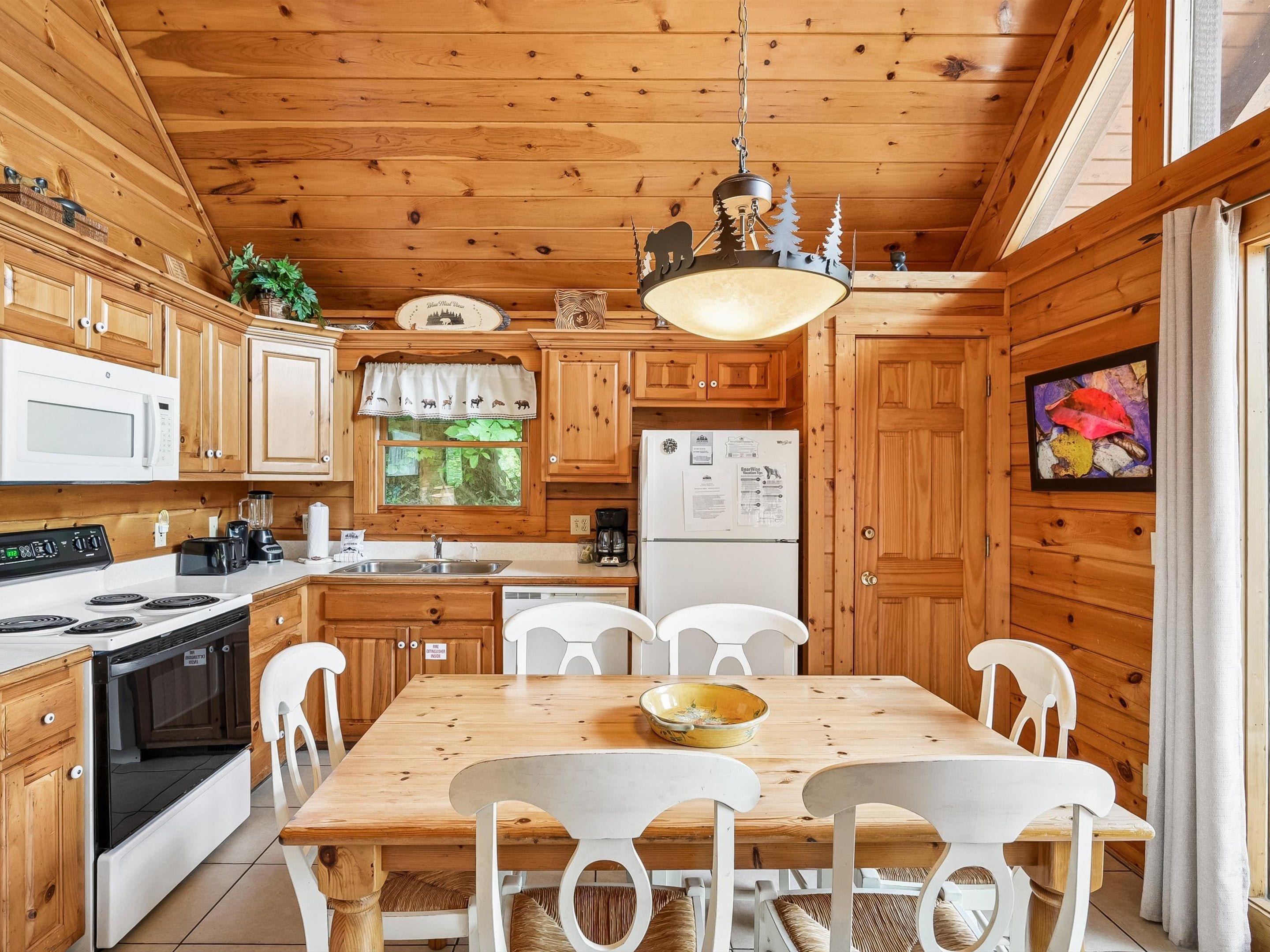 Cocina de cabaña de madera con una mesa de comedor, sillas, un refrigerador y una estufa.
