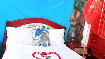Un lit avec une tête de lit bleue, une décoration représentant un dauphin, un ballon rouge et un arrangement floral en forme de cœur.