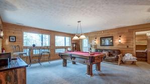 A wooden cabin interior with a pool table, a fireplace, and a cozy seating area. - Dreamscapes by Jackson Mountain Rentals (Gatlinburg)