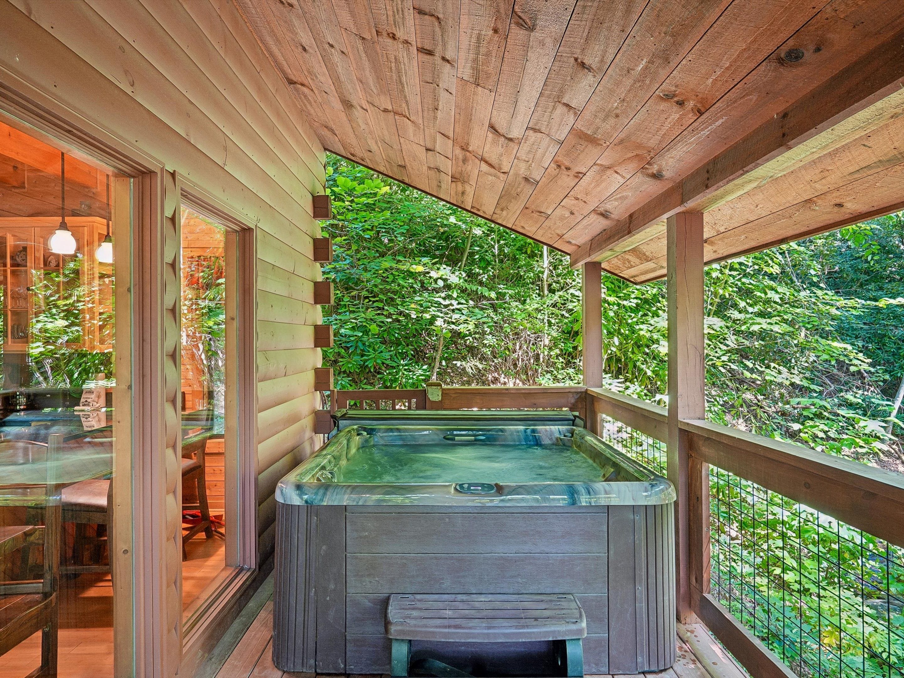 A hot tub in a wooden deck area with a view of dense greenery.
