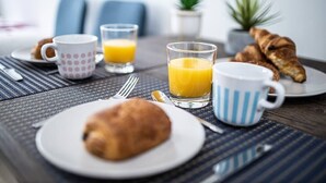 A breakfast setting with croissants, orange juice, and coffee cups on a table with a placemat. - Beautiful Break in Paris Gentilly (Gentilly)