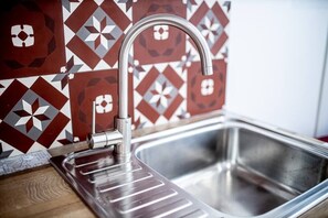 A stainless steel kitchen sink with a modern faucet, set against a patterned tile backsplash. - Beautiful Break in Paris Gentilly (Gentilly)