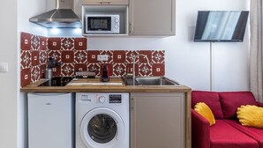 A compact kitchen with a washing machine, microwave, and a TV mounted on the wall. - Beautiful Break in Paris Gentilly (Gentilly)