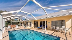 A pool area with a covered patio, lounge chairs, and a table. - Marco Beach Haven 2 blocks from South Beach! (Marco Island)