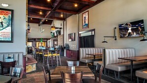Ein Restaurant mit Holztischen und -sitzen, einem Barbereich und einem Fernseher, der ein Sportereignis zeigt.