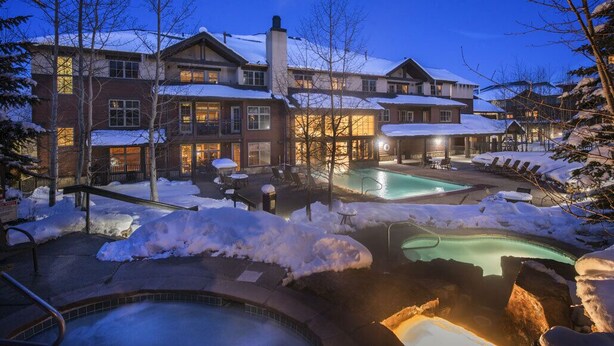 Ein Resort mit mehreren Gebäuden, Außenpools und schneebedeckter Landschaft.
