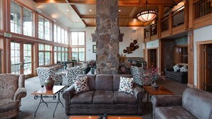 Eine geräumige Lobby mit einer Steinsäule, Ledersofas, gemusterten Sesseln und einem großen Fenster, das für natürliches Licht sorgt.