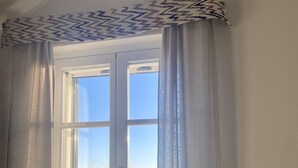 Een kamer met een raam, een radiator en een rieten stoel.