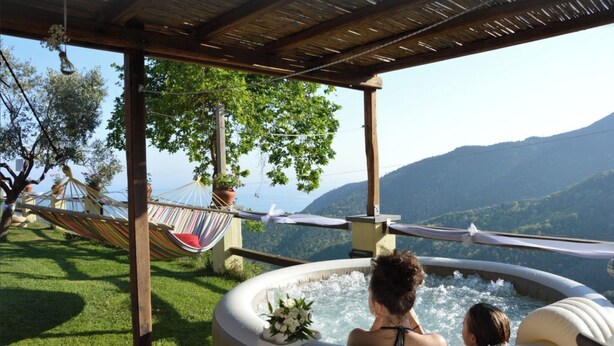 Een hottub met uitzicht op bergen, een hangmat en een houten pergola.
