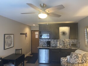Enjoy a stylish kitchen and dining area with a modern design, featuring a refrigerator, microwave, and comfortable seating.
