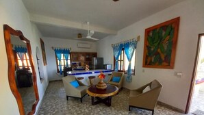 Ein Wohnzimmer mit einem gemusterten Boden, einem runden Couchtisch mit einer Vase, zwei Sofas und einer Küche im Hintergrund.