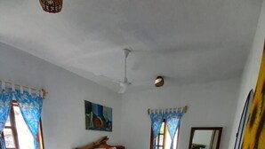 Ein Schlafzimmer mit zwei Betten, einem Schminktisch, einem Stuhl und einem Deckenventilator.
