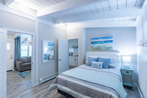 A bedroom with a bed, bedside table, and a painting on the wall.