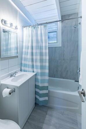 A bathroom with a white sink, mirror, and bathtub.