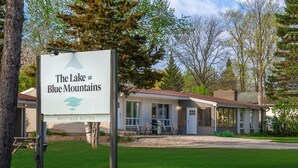 A sign for "The Lake at Blue Mountains Boutique Suites" with a view of a building with a covered patio and a lawn. - Mountain View Boutique Suite with contactless entry - The Lake at Blue Mountains (The Blue Mountains)