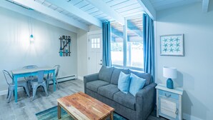 A living room with a gray sofa, wooden coffee table, blue chairs, and a small white nightstand with a lamp. - Mountain View Boutique Suite with contactless entry - The Lake at Blue Mountains (The Blue Mountains)