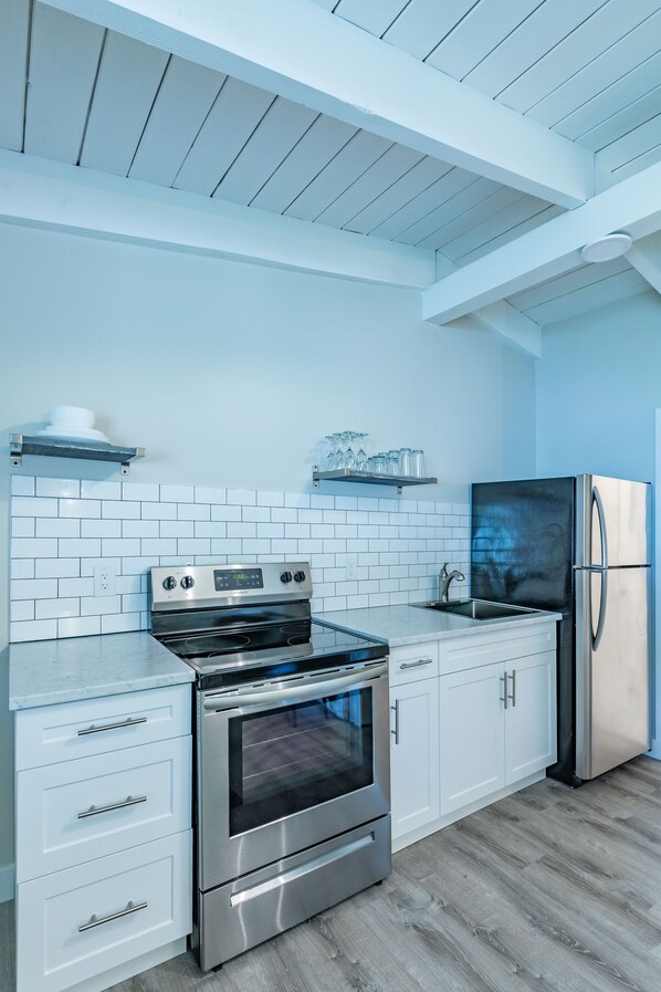 A modern kitchen with white cabinetry, a stainless steel oven, and a refrigerator.