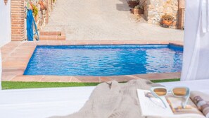 Vista di una piscina da un balcone, con un’area verde di fronte.