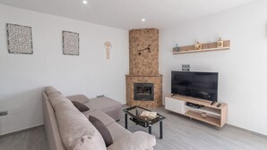 Una sala de estar moderna con un sofá color beige, una mesa de centro de vidrio, chimenea, televisor y arte decorativo en la pared.