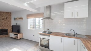 Una cocina moderna con gabinetes blancos, encimera de madera, horno integrado y un ventanal grande.