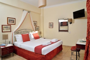 A neatly arranged hotel room with a bed, bedside tables, a TV, and a small table with a chair. - Agistri Hotel (Agistri)