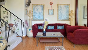 A living room with a red sofa, a coffee table, and a staircase with decorative railings. - Agistri Hotel (Agistri)