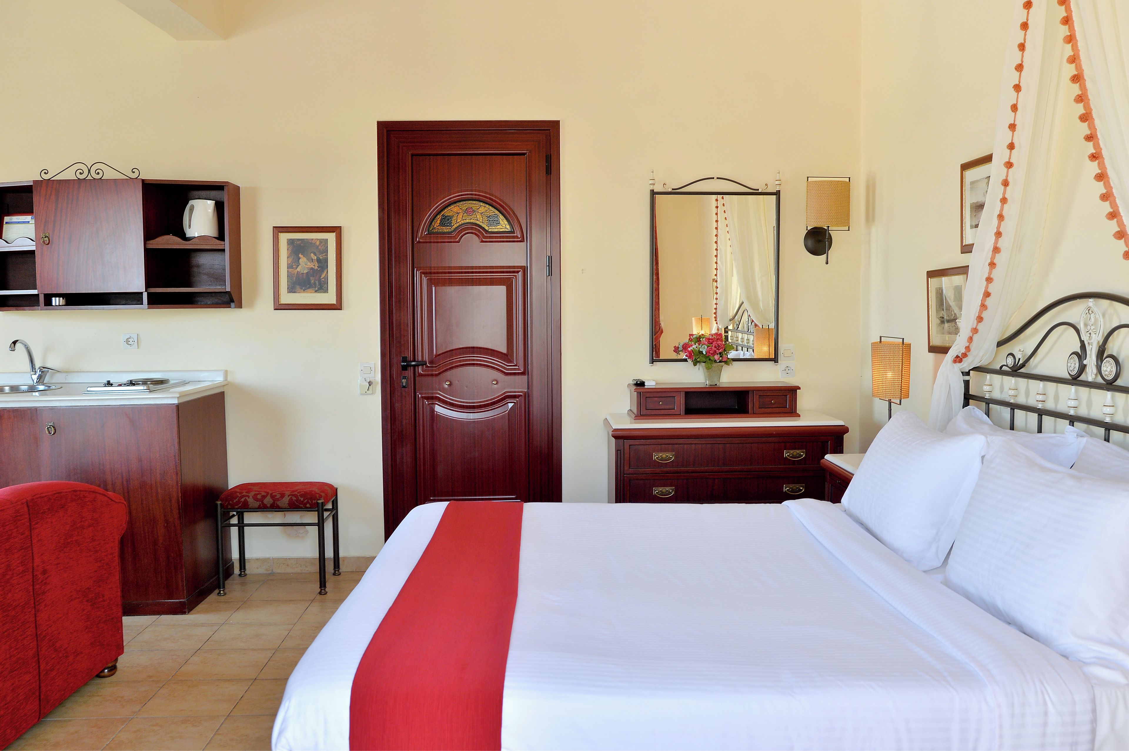 Ein Hotelzimmer mit Bett, Schreibtisch mit Spüle, Stuhl, Kleiderschrank und Spiegel.