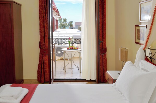 Une chambre d’hôtel avec un lit, une petite table avec des fruits, une chaise et un balcon avec vue.