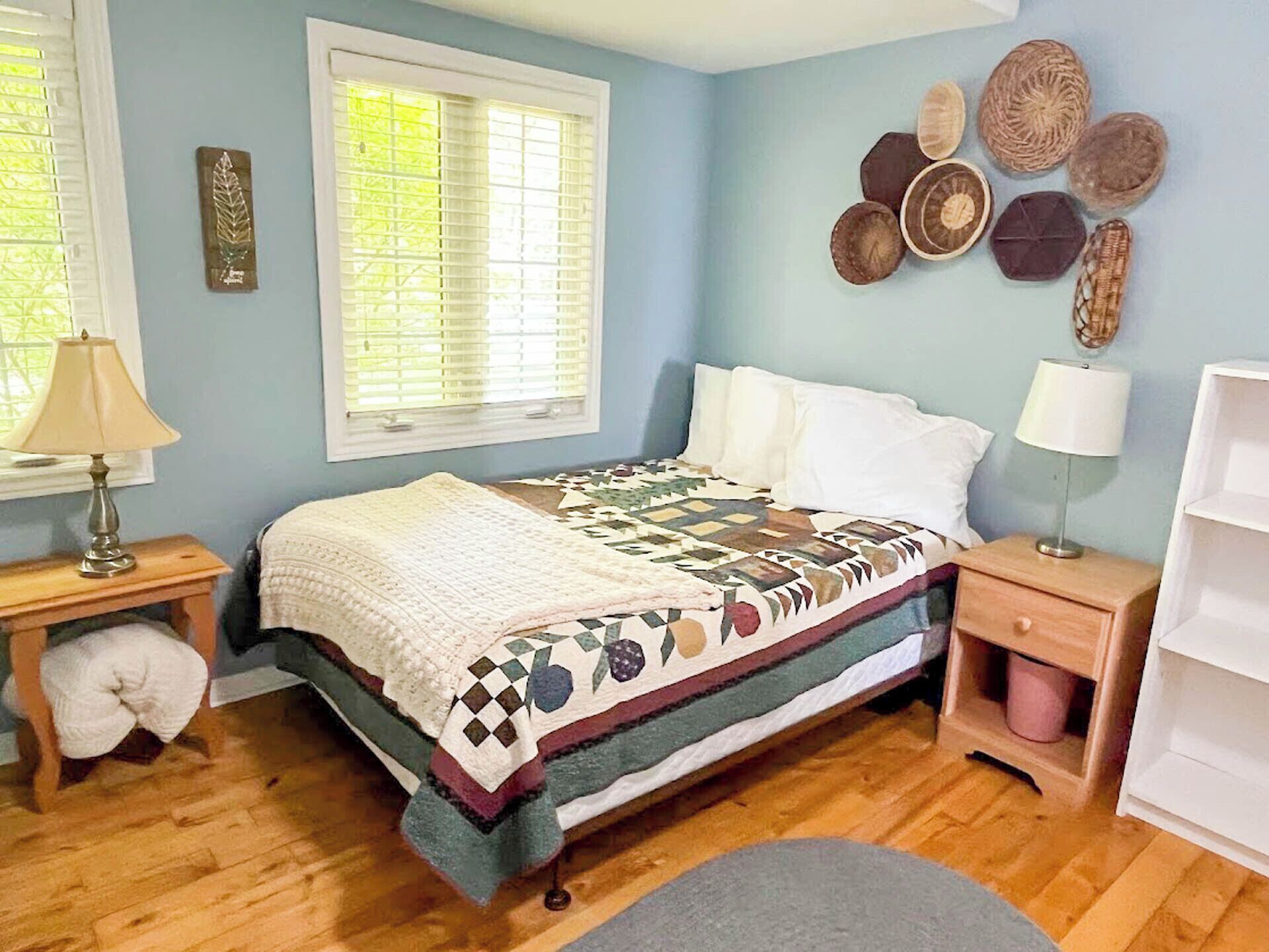 Een slaapkamer met een bed, twee nachtkastjes, een raam met zonwering en decoratieve wandpanelen.