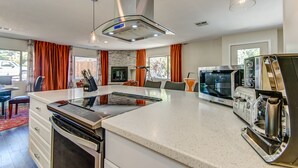 A modern kitchen with a central island, built-in appliances, and a dining area with orange curtains. - Agave House, Views Of Chimney Rock, Pets OK! (Sedona)