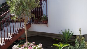 Un balcon agrémenté de plantes en pot et doté d’une rambarde en métal.