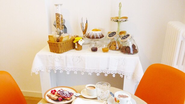 Une table mise pour le petit-déjeuner, avec des viennoiseries, du café et une assiette de fruits.