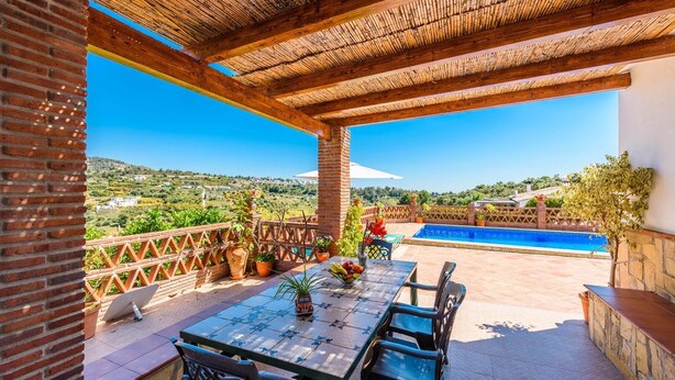 A covered patio with a table and chairs, a pool, and a view of the countryside. - Villa Noelia Frigiliana by Ruralidays (Málaga)