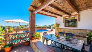 A terrace with a pool, outdoor seating, and potted plants. - Villa Noelia Frigiliana by Ruralidays (Málaga)