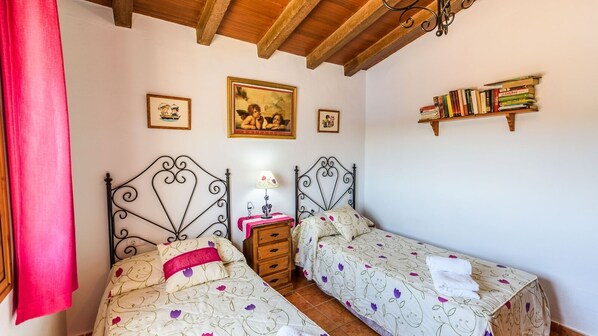 Un dormitorio con dos camas, techo de madera, una estantería y una pared adornada con marcos.