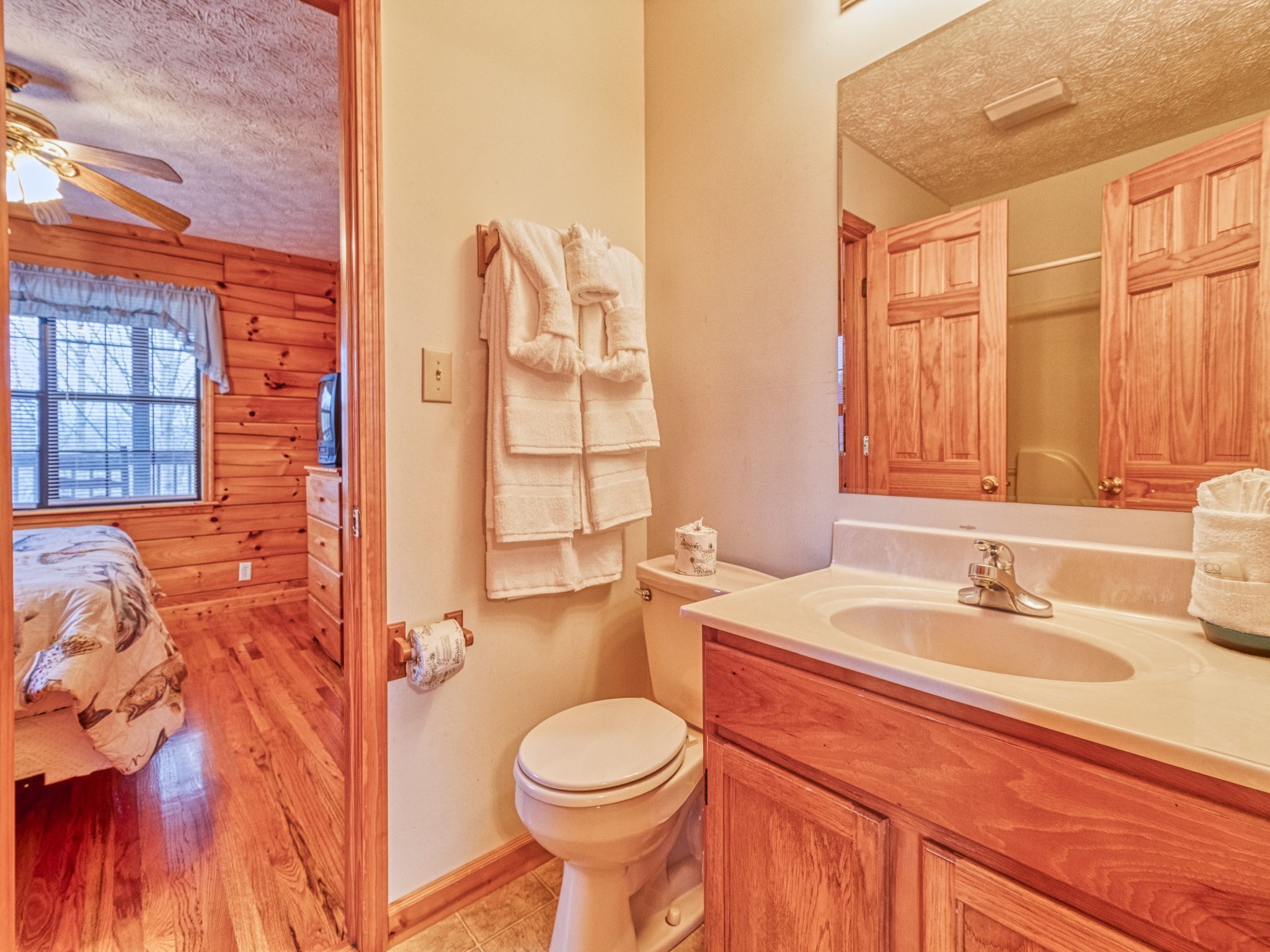 A bathroom with wooden cabinets, a sink, and a toilet.