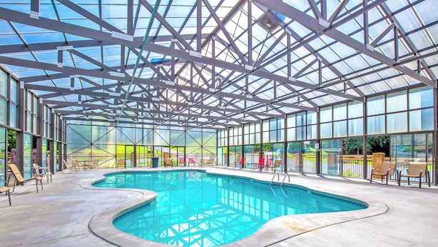An indoor swimming pool with a glass ceiling, surrounded by chairs and tables. - Hawks Point Lodge by Jackson Mountain Rentals (Sevierville)