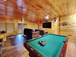 A pool table with balls, a television, and a seating area with sofas. - Hemlock Inn by Jackson Mountain Rentals (Gatlinburg)