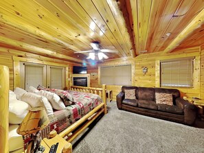 L’intérieur d’un chalet confortable, avec un lit, un canapé, un téléviseur et une cheminée.