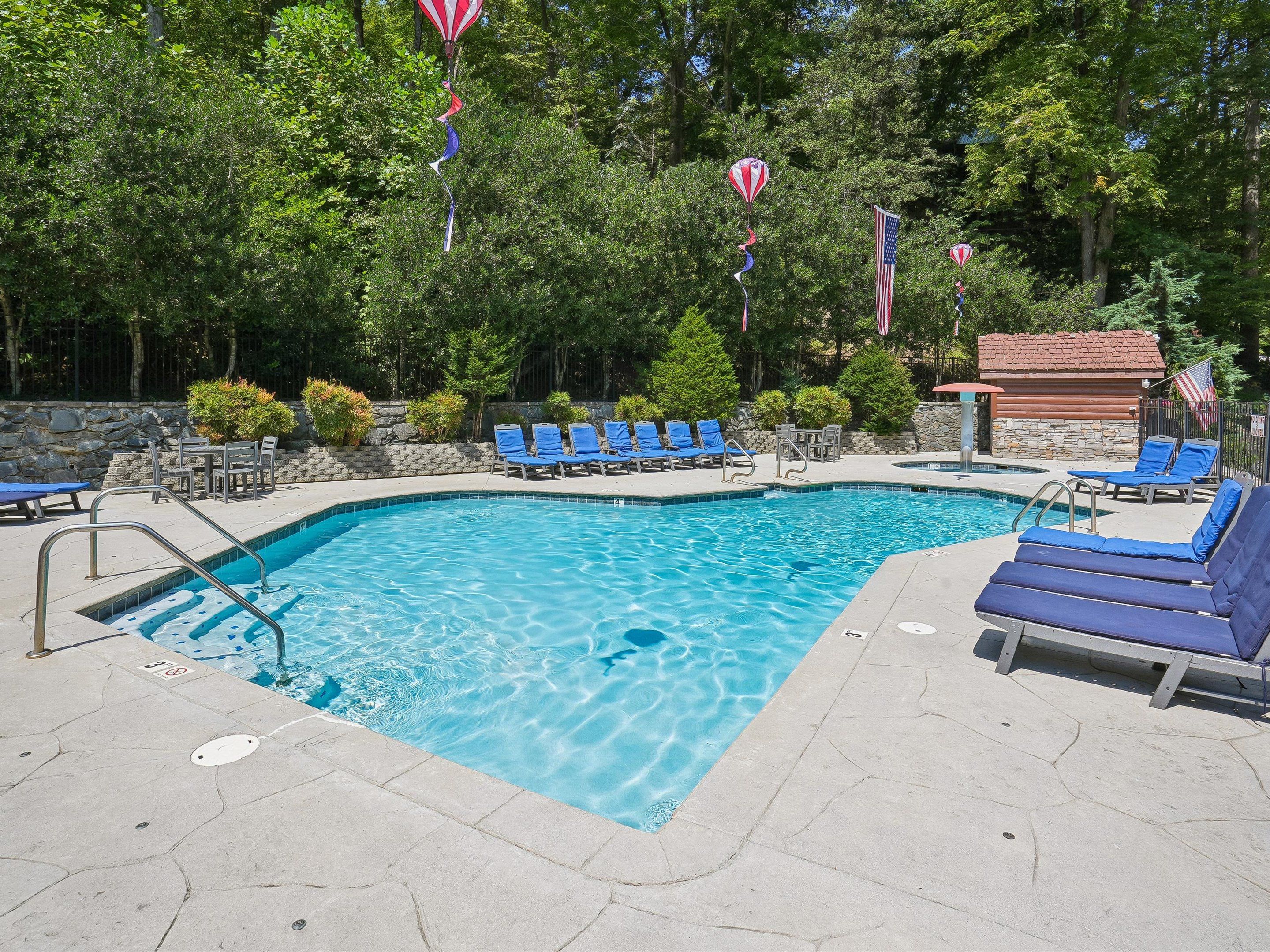 A swimming pool with blue lounge chairs and a stone wall.